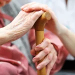 Senior woman holding care giver's hands